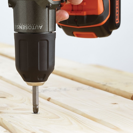 Photo of BLACKDECKER ASD184K cordless drill driving screw into light wood surface, close-up angle.