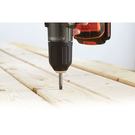 BLACKDECKER ASD18KB cordless drill driving a screw into light wood planks, close-up side angle.