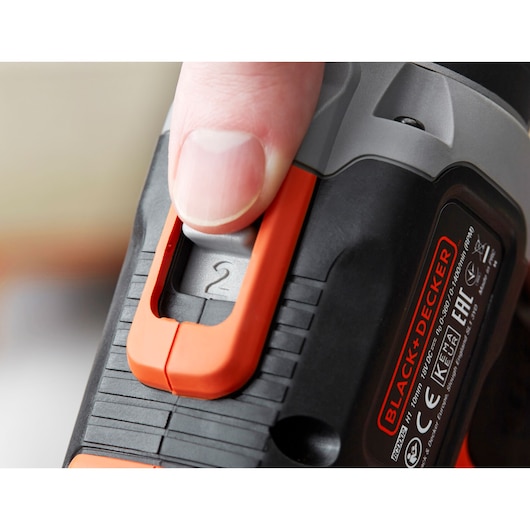 Close-up photo of a BLACK+DECKER BCD003ME2K drill with a finger adjusting the orange speed selector.