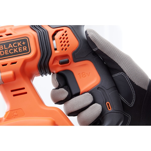 Close-up of BLACK+DECKER 18V cordless drill handle, SKU BCD900M1K, held by gloved hand, front angle.