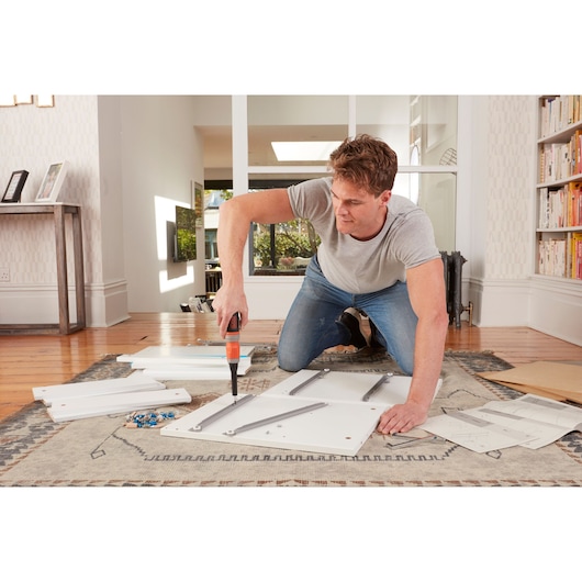 BLACKDECKER BCF602C cordless screwdriver used for furniture assembly on living room floor.
