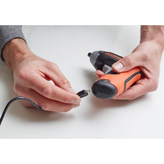 Photo of BLACKDECKER BCF611CK cordless screwdriver being charged with a USB cable, close-up on white background.