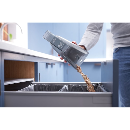 Photo of BLACK+DECKER BCHV001C1 handheld vacuum being emptied into a kitchen trash bin.