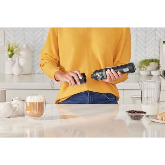 Photo of BLACK+DECKER BCKM1012KB handheld milk frother in use on a kitchen counter with coffee and accessories.