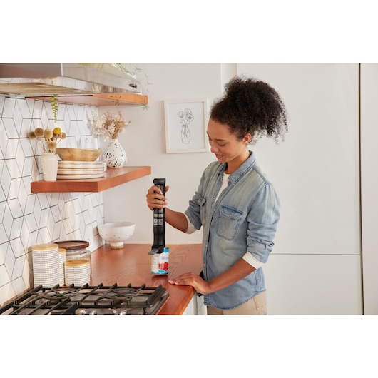 Photo of BLACKDECKER BCKM1012KB hand mixer used in a kitchen by a person standing near a stove.