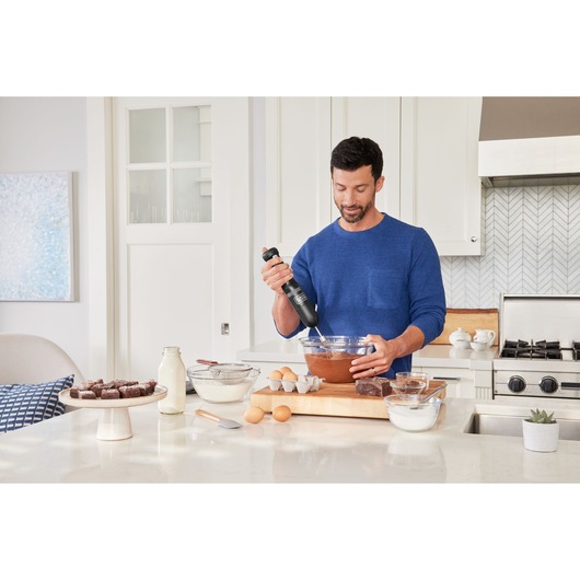 BLACKDECKER BCKM1012KB hand mixer in use mixing batter in glass bowl on kitchen counter.