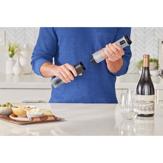 Photo of BLACKDECKER electric spice grinder BCKM1012KG held in hand, kitchen setting, food and wine nearby.