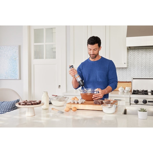 BLACKDECKER BCKM1012KG hand mixer used to mix batter in a glass bowl in a modern kitchen setting.