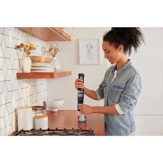 Photo of BLACKDECKER electric can opener BCKM1016KSB in use on a kitchen counter beside stove.