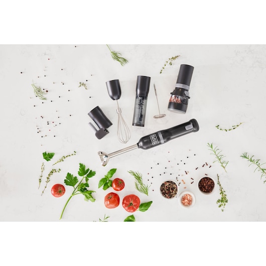 Photo of BLACK+DECKER BCKM1016KSB multi-accessory hand blender set with attachments and fresh herbs on white surface.