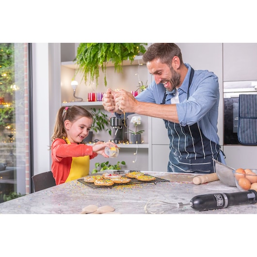 BLACKDECKER BCKM1016KSB hand mixer on kitchen counter with cupcakes and baking tools, father and daughter decorating.