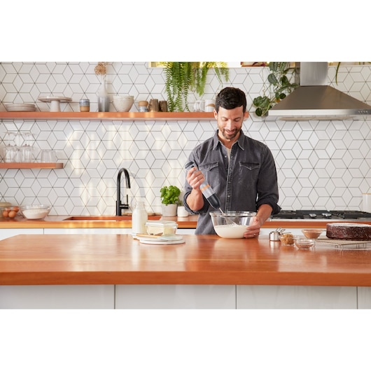 Photo of BLACKDECKER BCKM1016KSG hand mixer being used to mix batter in a glass bowl on a modern kitchen counter.