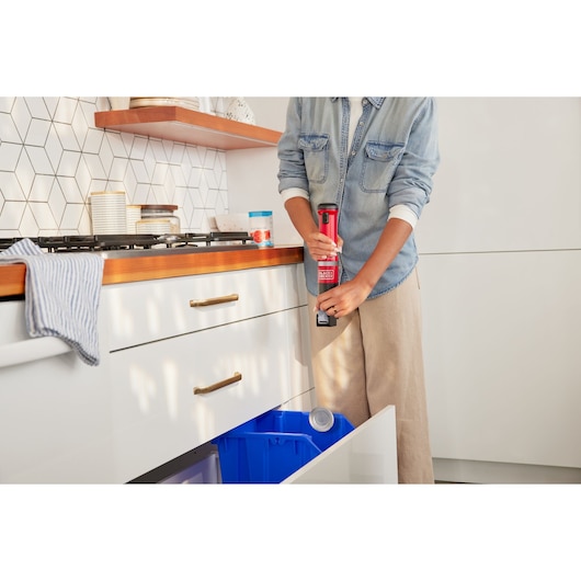 Photo of a person using a BLACKDECKER BCKM1016KSR handheld tool to open a can in a modern kitchen setting.