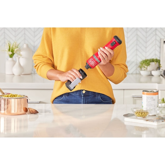 Photo of BLACKDECKER BCKM1016KSR cordless electric can opener in red, held in a kitchen setting.