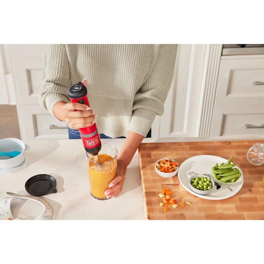 BLACKDECKER immersion blender BCKM1016KSR in use blending orange liquid in glass, kitchen counter scene