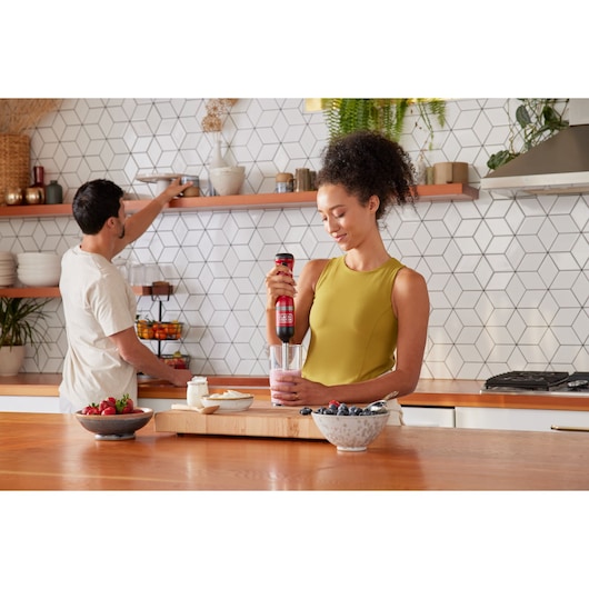 Photo of BLACKDECKER BCKM1016KSR hand blender mixing smoothie in modern kitchen with fresh fruit on countertop.
