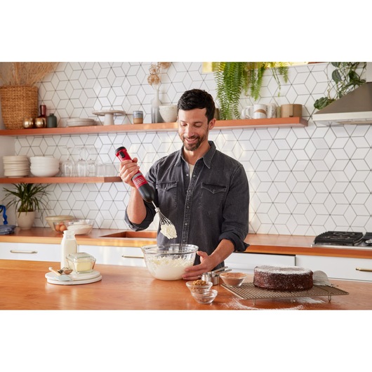 BLACKDECKER BCKM1016KSR hand mixer in use in a kitchen, mixing batter in a glass bowl.