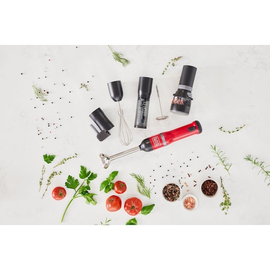 BLACK+DECKER BCKM1016KSR red hand blender set with multiple attachments and fresh herbs, photographed top-down.