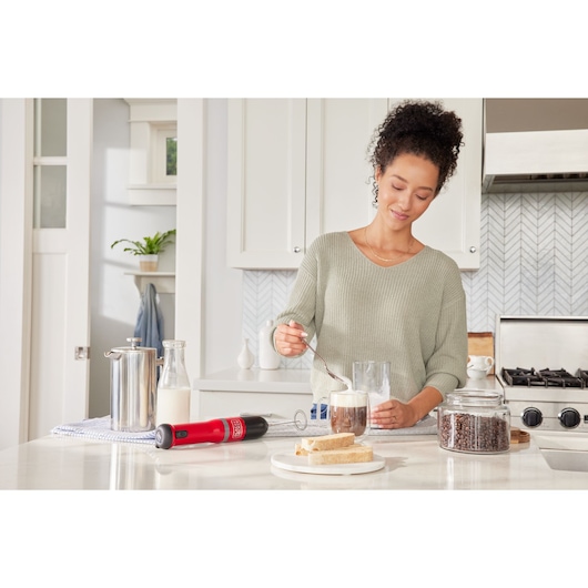 BLACKDECKER BCKM101MFFF milk frother on kitchen counter with coffee, milk, bread, and coffee beans.