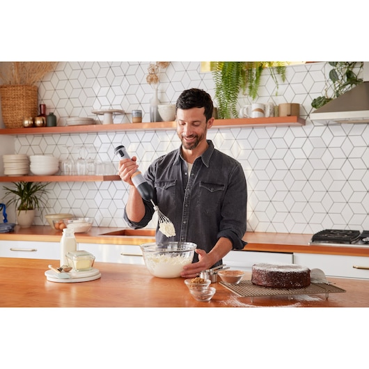 BLACKDECKER BCKM101WHFF hand mixer used to whip ingredients in glass bowl in kitchen, cake on cooling rack.