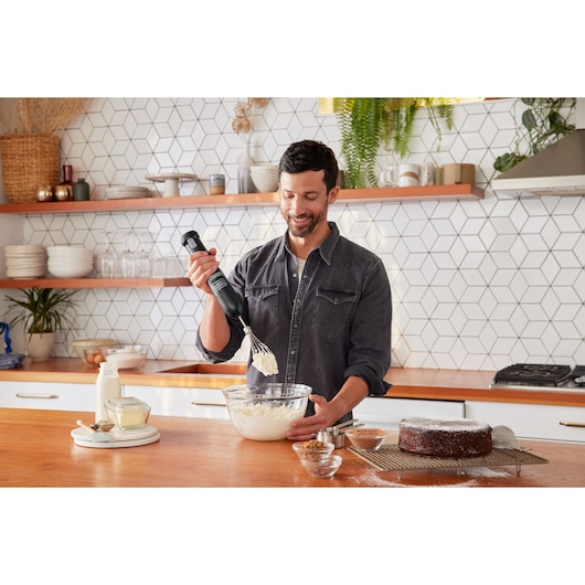 BLACKDECKER BCKM101WHFF hand mixer used to whisk ingredients in a glass bowl in a modern kitchen.