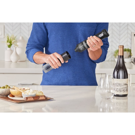 Photo of BLACKDECKER electric wine opener BCKM101WNFF in use, with wine bottle, glasses, and cheese board on counter.