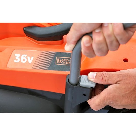 Close-up of BLACK+DECKER BCMW3336L2 lawn mower handle adjustment with visible 36V label and orange housing.