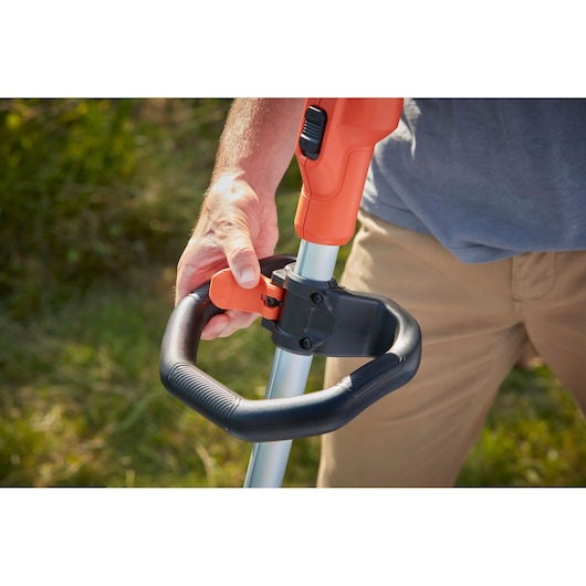 Photo of a BLACK+DECKER BCSTA536L1 grass trimmer handle being adjusted outdoors, close-up view.