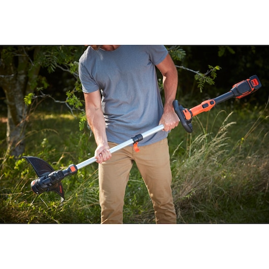 BLACKDECKER BCSTE636L1 cordless grass trimmer with black and orange accents, shown in outdoor use.