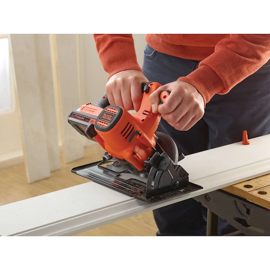 Photo of BLACKDECKER BDCCS18 cordless circular saw cutting wood, orange and black design, handheld use.