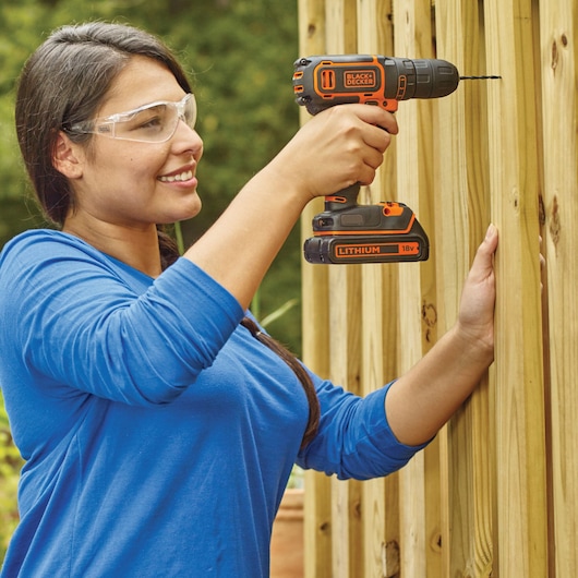 Photo of BLACKDECKER BDCDC18K1B cordless drill being used to drill into wooden beams outdoors.