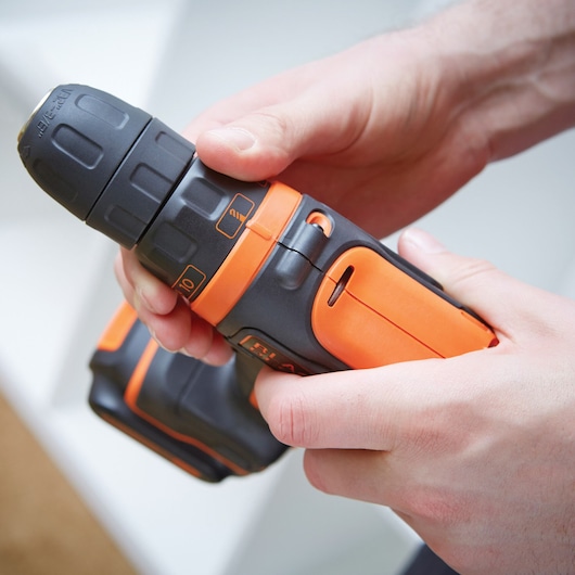 Close-up of BLACKDECKER BDCDD12K cordless drill with orange and black casing held in hands.