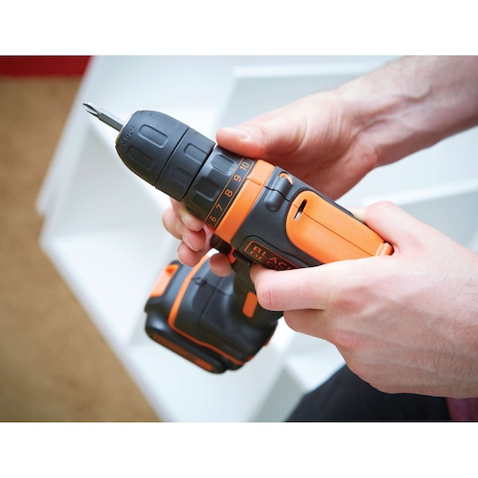 Photo of BLACKDECKER BDCDD12 cordless drill, orange and black, held in hand during use.