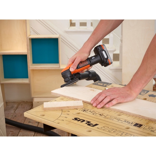 Photo of BLACK+DECKER BDCDS12N cordless sander in use on plywood in a workshop setting.
