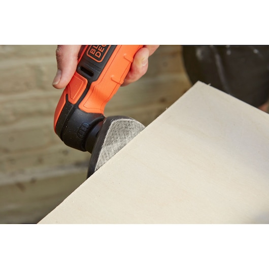 Photo of BLACK+DECKER BDCDS12N detail sander sanding the edge of a wooden board, close-up in use.