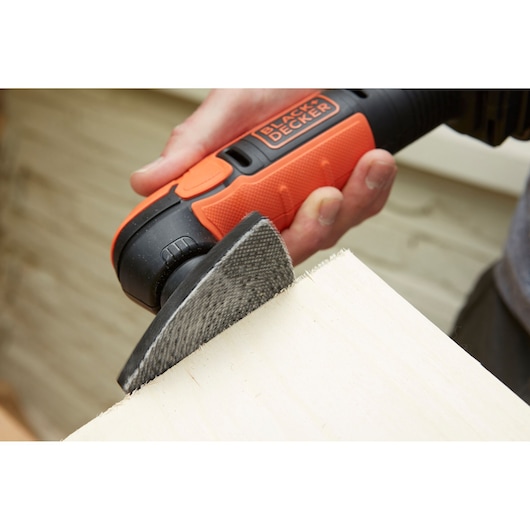 Photo of BLACK+DECKER BDCDS12S1 cordless sander sanding the edge of a wooden board handheld.