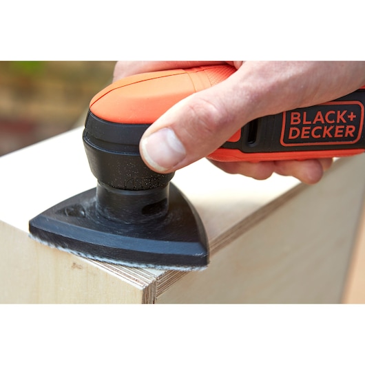 Photo of BLACK+DECKER BDCDS12S1 sander smoothing wood edge in close-up handheld action.