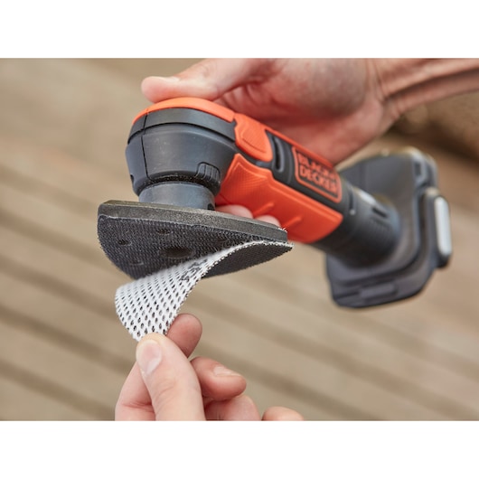 Photo of BLACKDECKER BDCDS12S1 cordless detail sander with mesh sanding sheet being attached, handheld close-up.