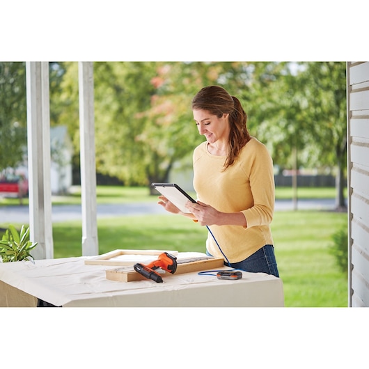 Photo of BLACKDECKER BDCGG12S1 cordless glue gun on a table with wood pieces outdoors.
