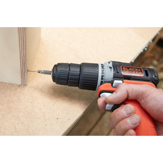 BLACKDECKER BDCHD12S1 cordless drill in use, driving a screw into plywood panel, close-up photography.