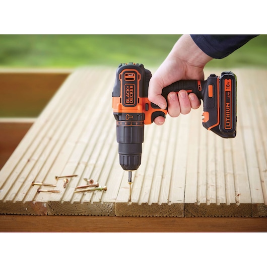 Photo of BLACKDECKER BDCHD18 cordless drill with 18V lithium battery drilling into wooden planks.