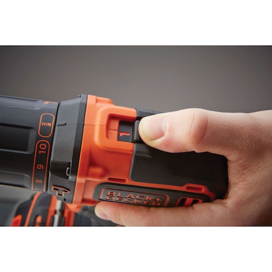Close-up of a hand adjusting speed on a BLACK+DECKER cordless drill BDCHD18, showing orange and black details.