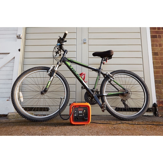 Photo of BLACKDECKER BDCOM400 portable power station charging a bicycle outdoors, front angle.