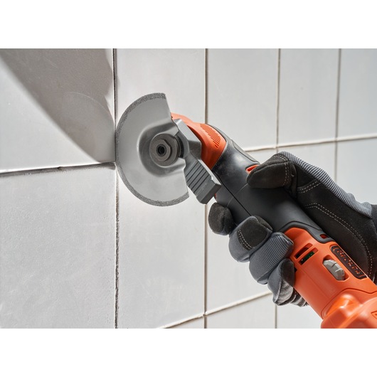 BLACK+DECKER BDCOS18N cordless oscillating multi-tool cutting tile grout, close-up side view.