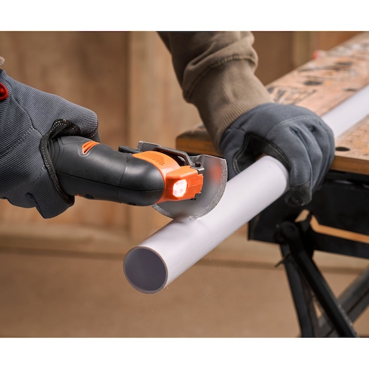 BLACK+DECKER BDCOS18N compact cordless saw cutting white plastic pipe, close-up action shot.