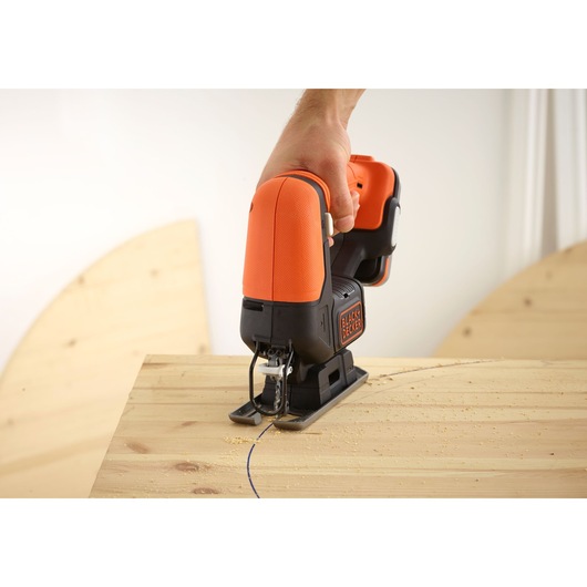 BLACKDECKER BDJ12 jigsaw in use cutting curved line on light wood surface, close-up.
