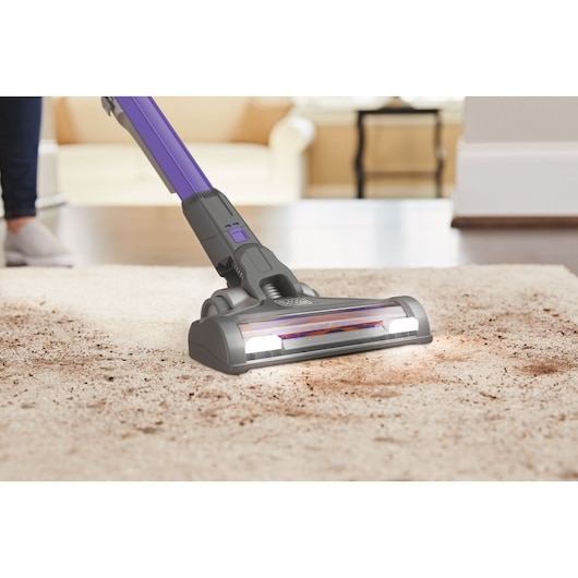 BLACKDECKER BDPSE1815P vacuum cleaner head cleaning dirt from beige carpet in living room, side angle