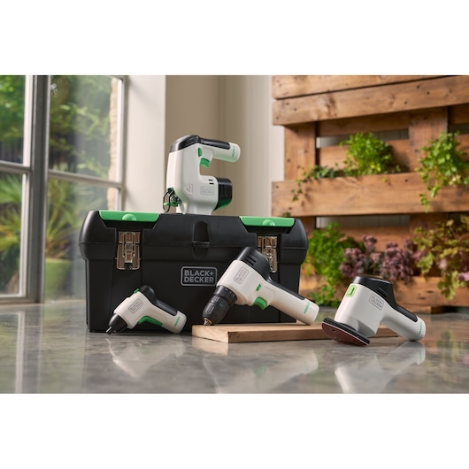BLACK+DECKER BDST60120 tool set with black and green toolbox, cordless drill, sander, and screwdriver on indoor floor.