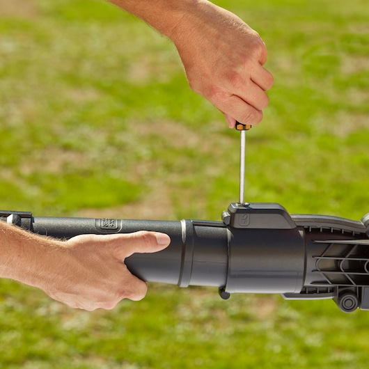 BLACKDECKER BEBLV301 leaf blower tube being assembled outdoors with screwdriver.