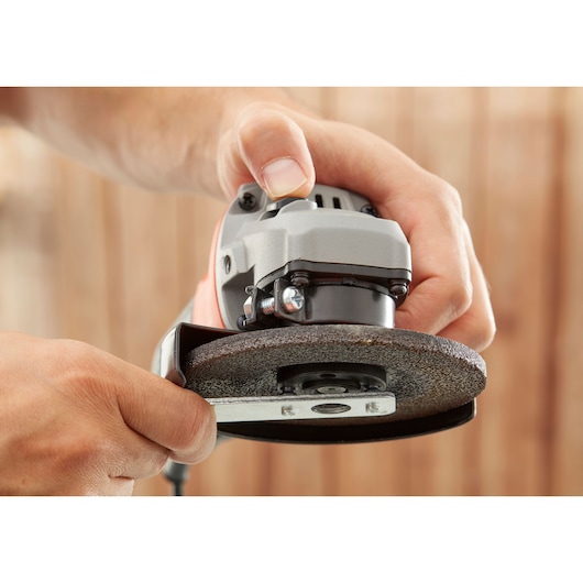 Close-up photo of BLACKDECKER BEG010K angle grinder held in hand, showing grinding disc and guard.